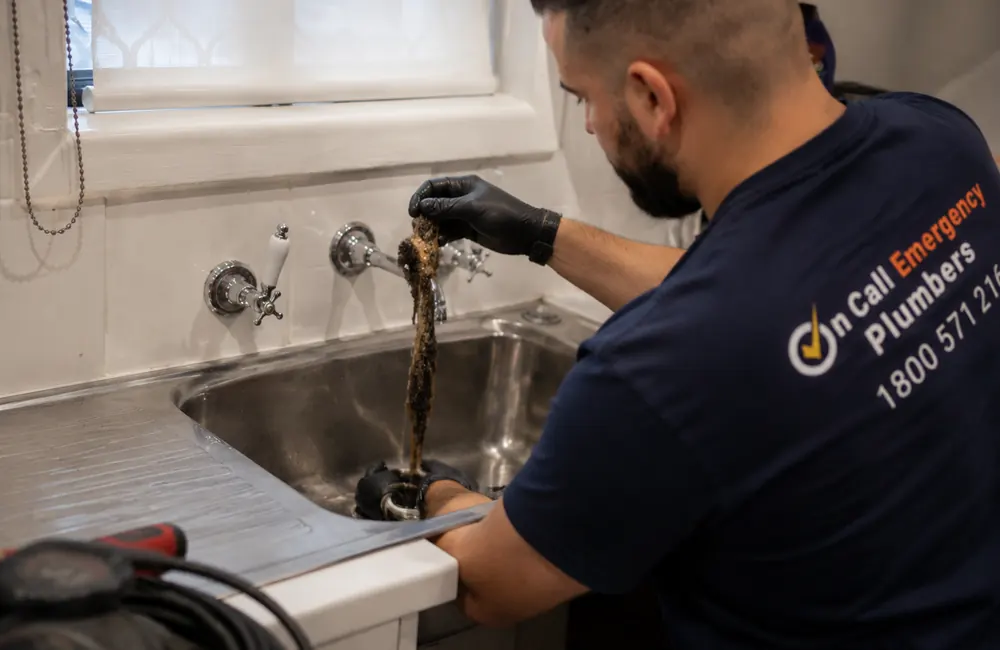 Plumber removing a kitchen sink drain blockage